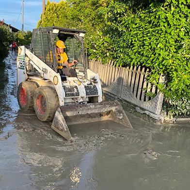 I byen Cesena, et af de værst ramte områder, fjerner et hold VM’er mudder og murbrokker fra gaderne ved hjælp af en Bobcat-bulldozer og en lastbil. De bragte det til lossepladser sammen med møbler fra hjem og virksomheder der blev beskadiget under oversvømmelsen.