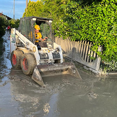 In the city of Cesena, one of the worst-hit areas, a team of VMs clear mud and debris from the streets with the aid of a Bobcat bulldozer and a truck. They brought this to landfill sites, along with flood-damaged furniture removed from homes and businesses.