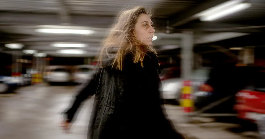 Woman running in a parking structure, bags under her eyes, blur edge of images