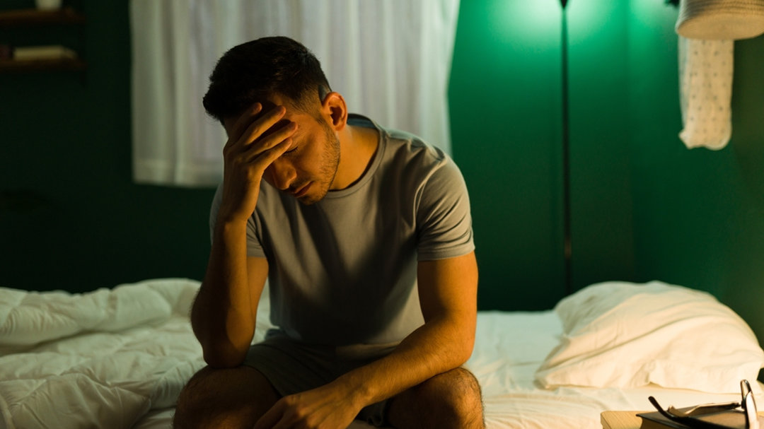 Man depressed, sitting up in his bed