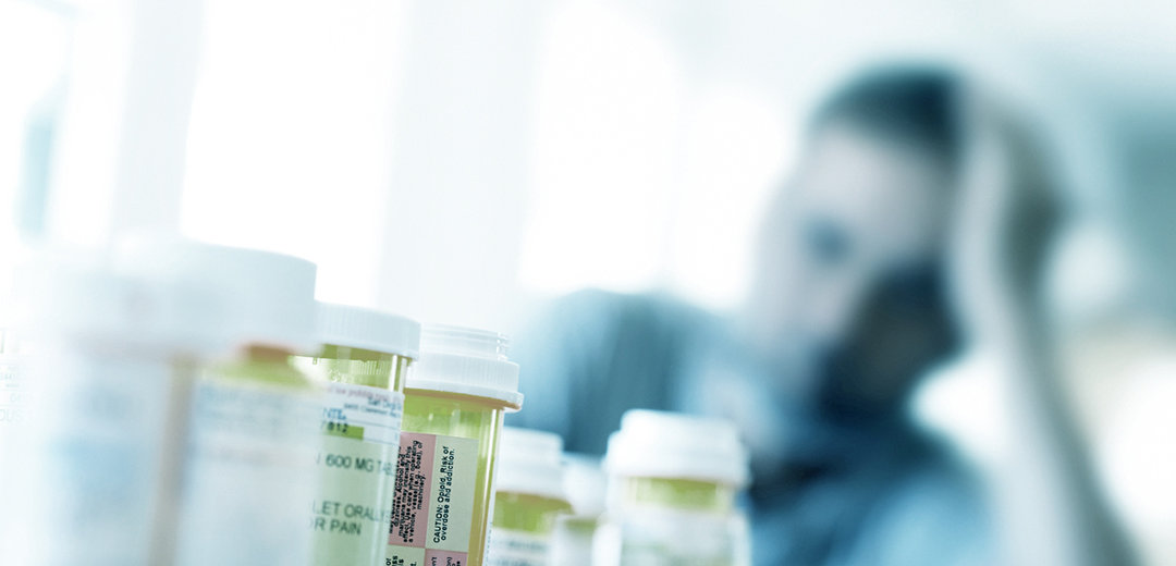 Prescription bottles in foreground, man, blurred - in background