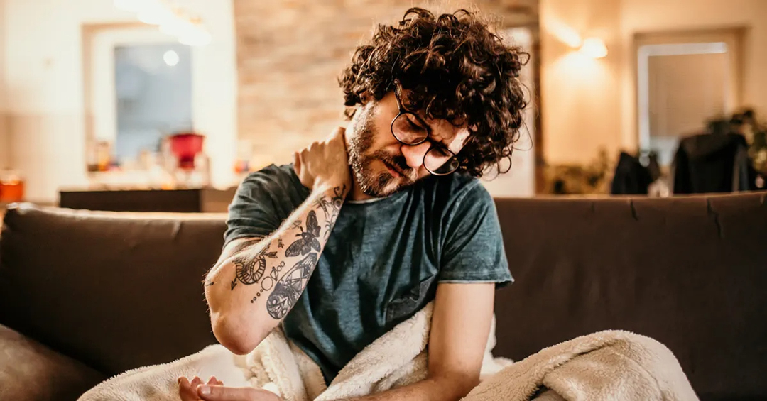 Man sitting up in bed, rubbing his neck in pain