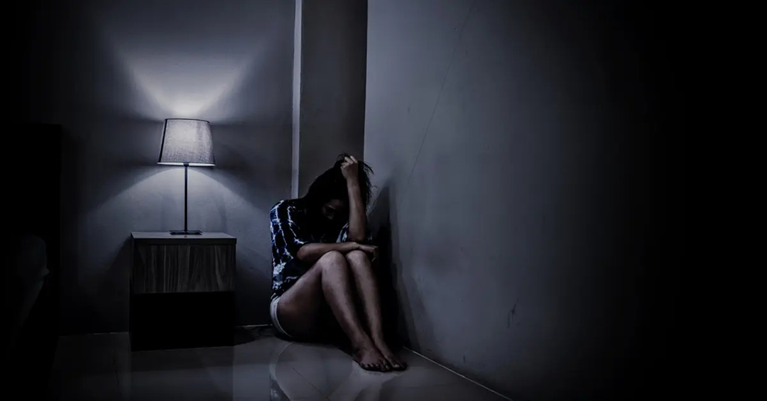 Woman sitting on floor in the corner of a room