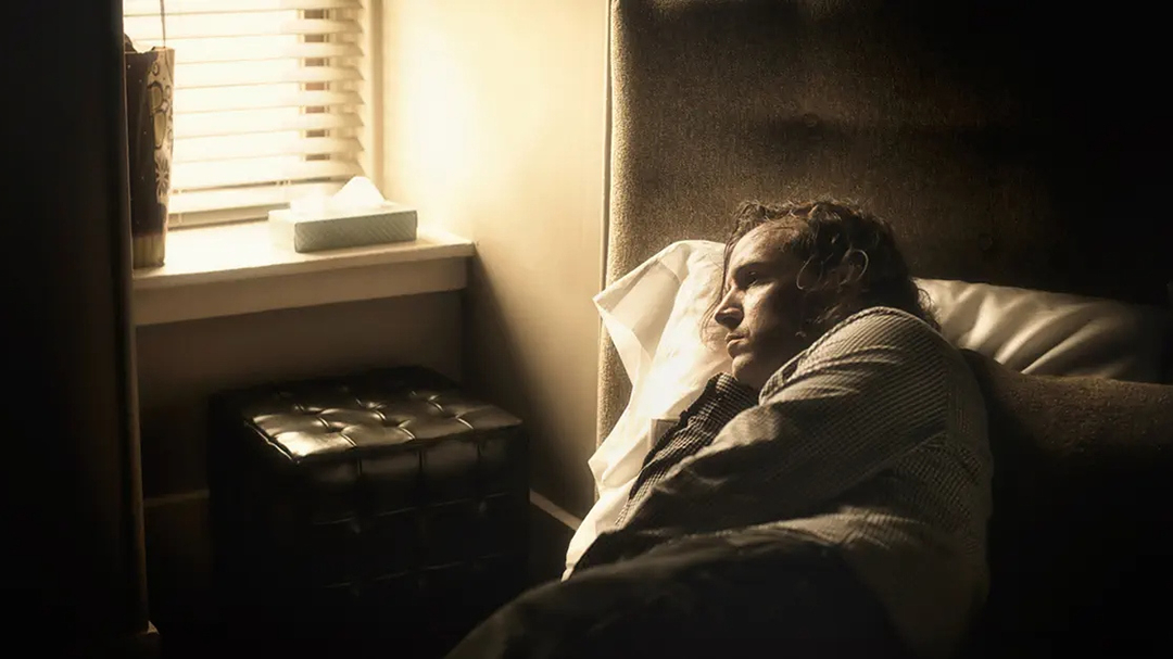 Man lying in bed looking through window