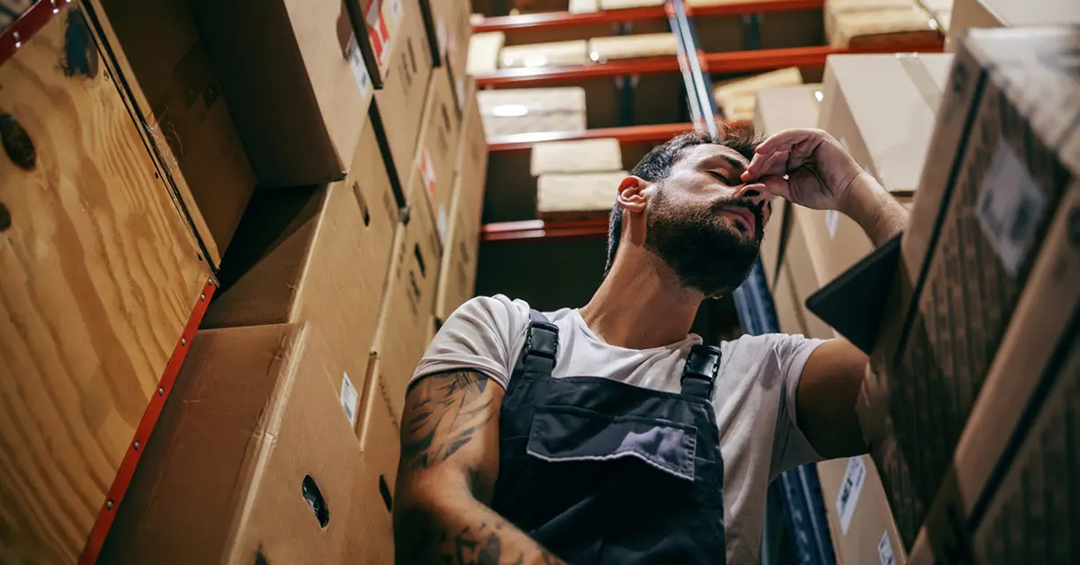 A man working in a stock area, tired and in pain