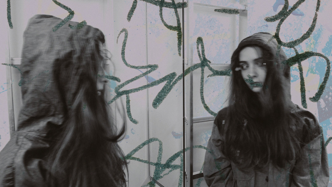 Young teenager staring at herself in a graffiti covered mirror