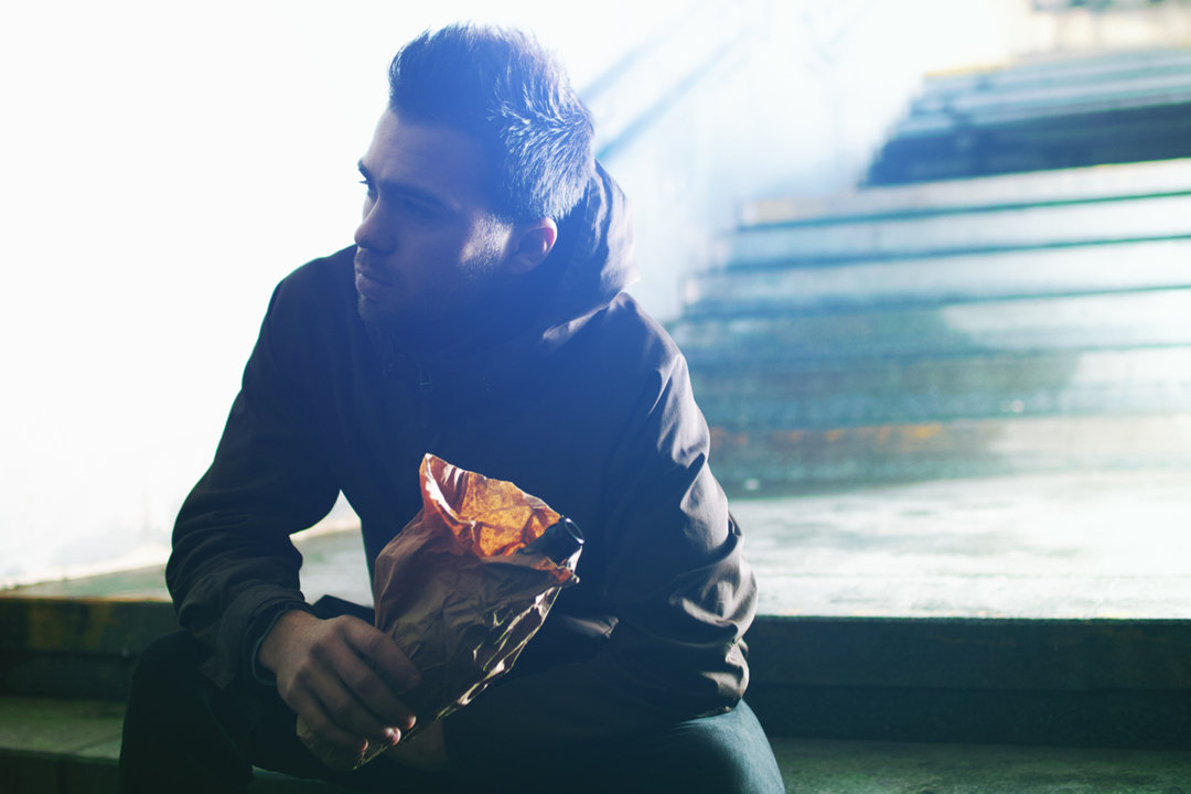 Man sitting with a bottle in a paper bag