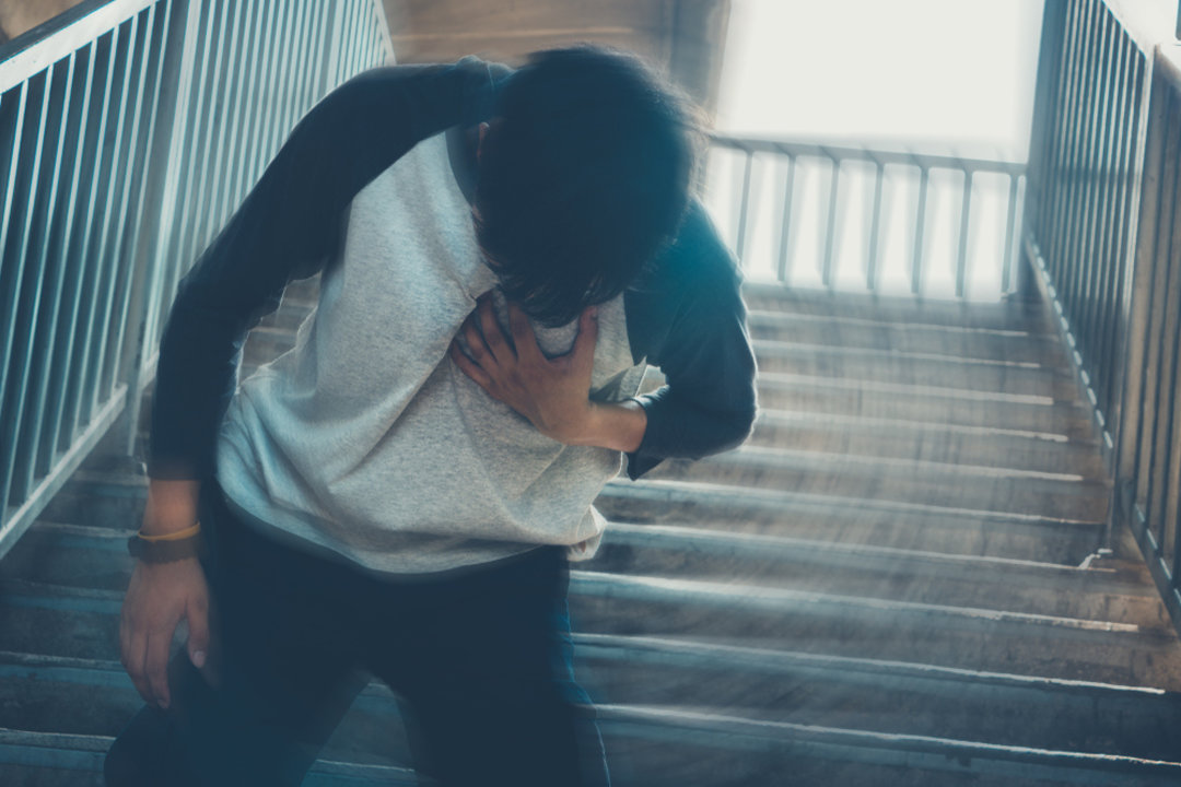 Man on stairs suffering and holding hand over chest