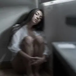 Woman sitting on a bathroom floor in a daze