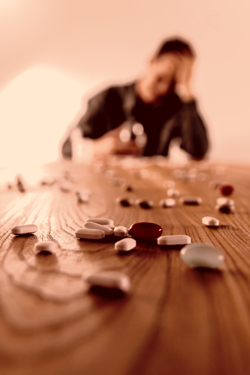 Pills on a table top with a close up of alcohol in the background