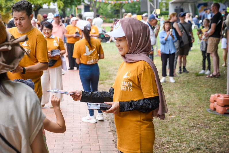A young Hazara woman shares a human rights booklet.