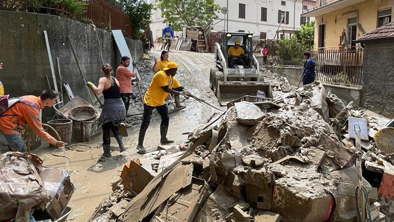 I byen Cesena, et af de værst ramte områder, fjerner et hold VM’er mudder og murbrokker fra gaderne ved hjælp af en Bobcat-bulldozer og en lastbil. De bragte det til lossepladser sammen med møbler fra hjem og virksomheder der blev beskadiget under oversvømmelsen.