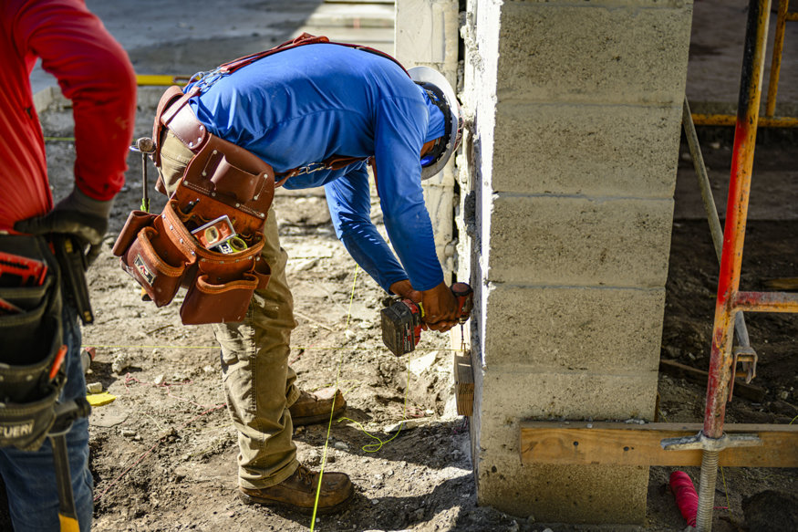Worker uses drill to secure footing layout line.