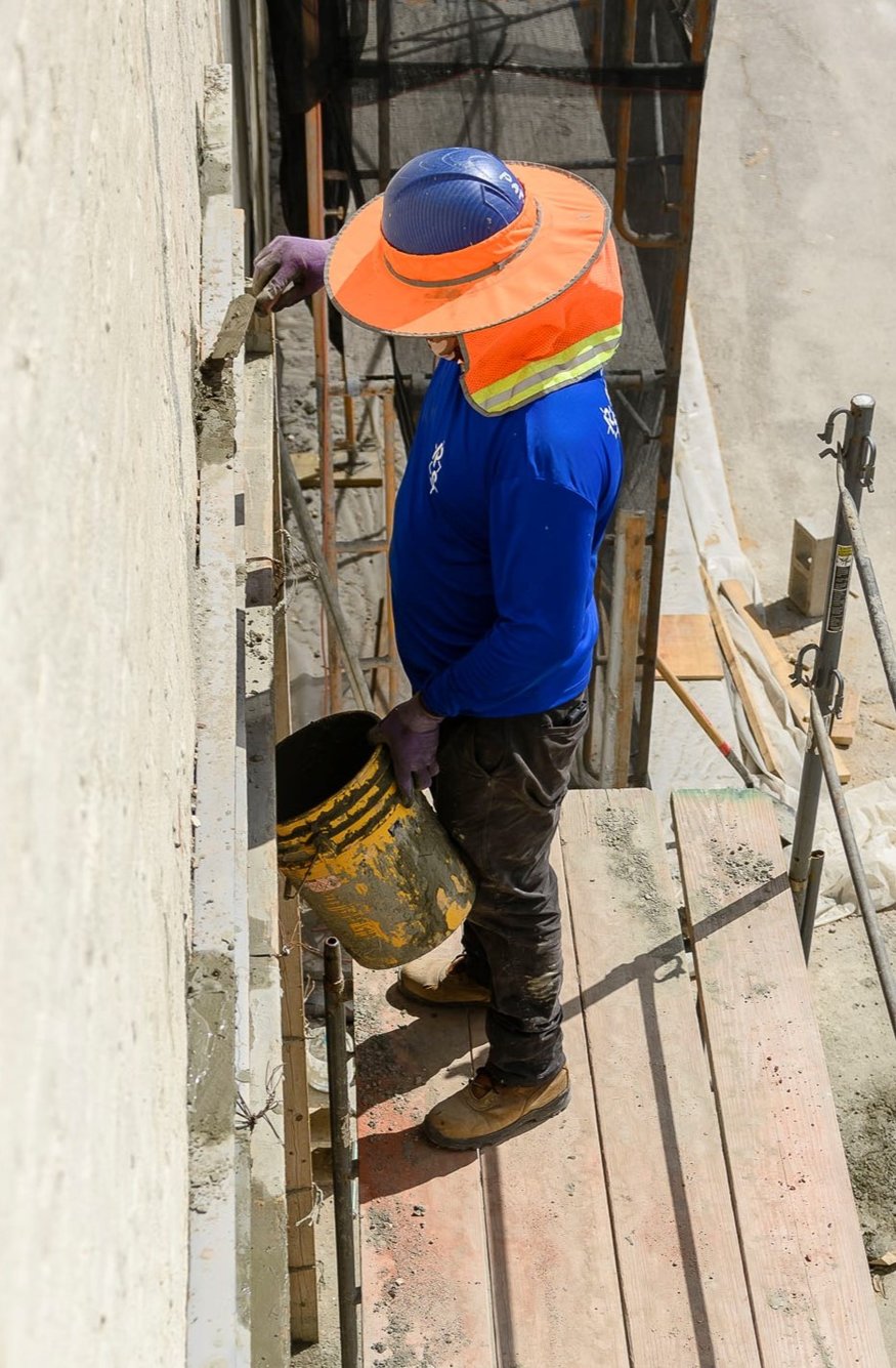 Crews fill void between wall and new frame with concrete.