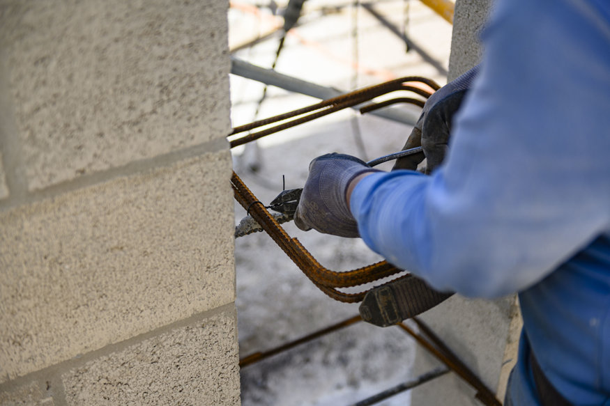 Worker secures steel ties around reinforcing bars.