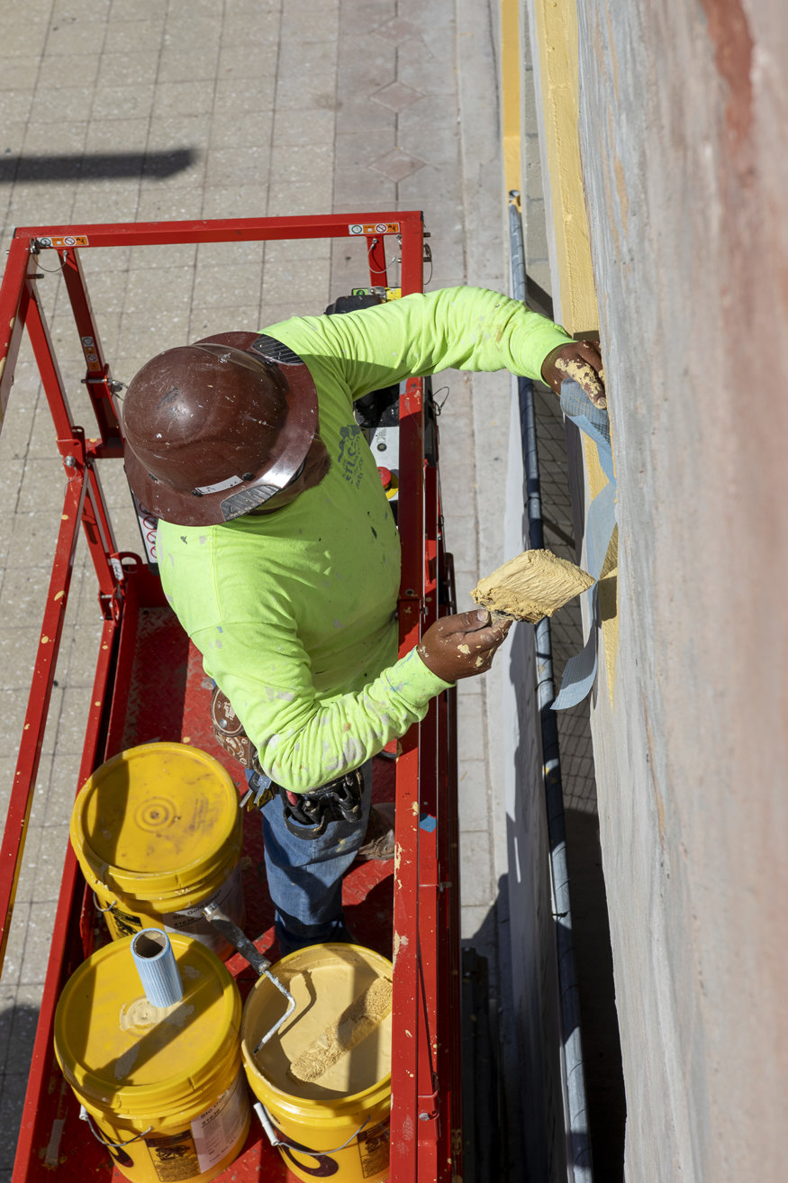 Worker brushing waterproof primer on window frame.
