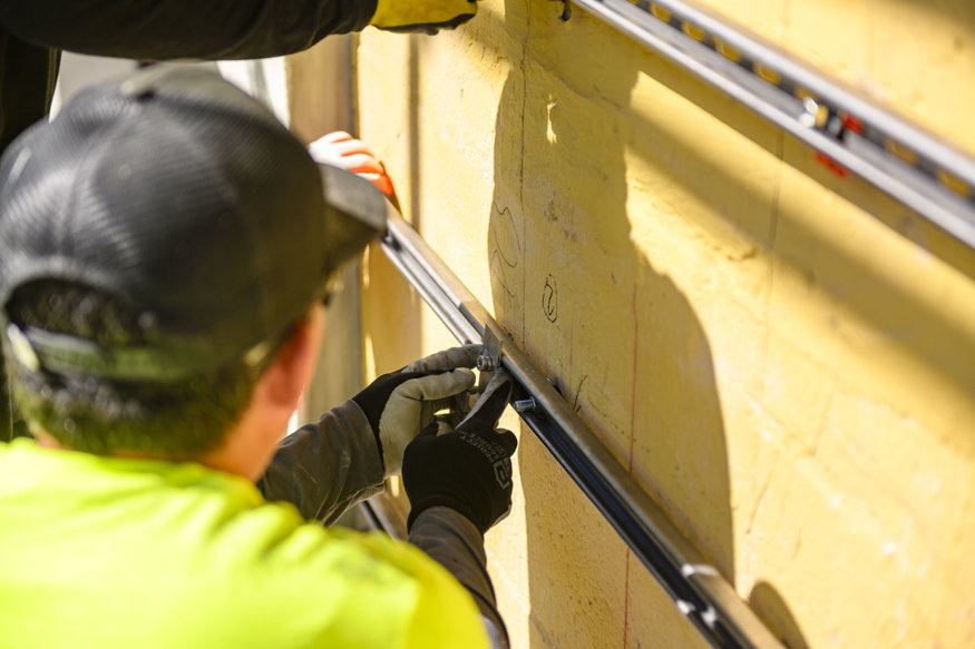 Worker securing mounting brackets on exterior wall.