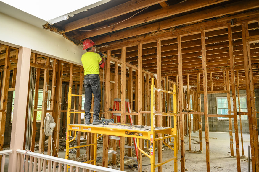 Worker removes ceiling materials from scaffold inside historic Brown Brothers Building. 