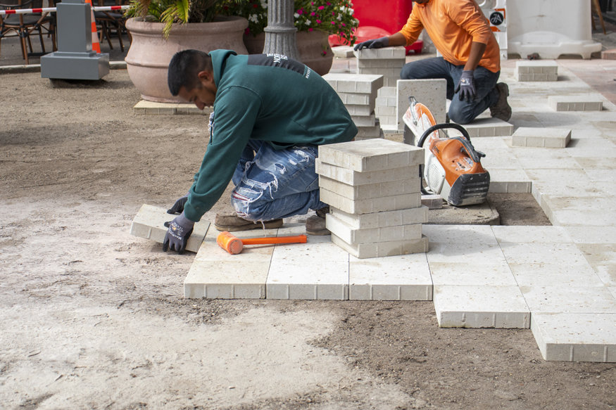Crews laying new pavers in front of the Telephone Building entrance.