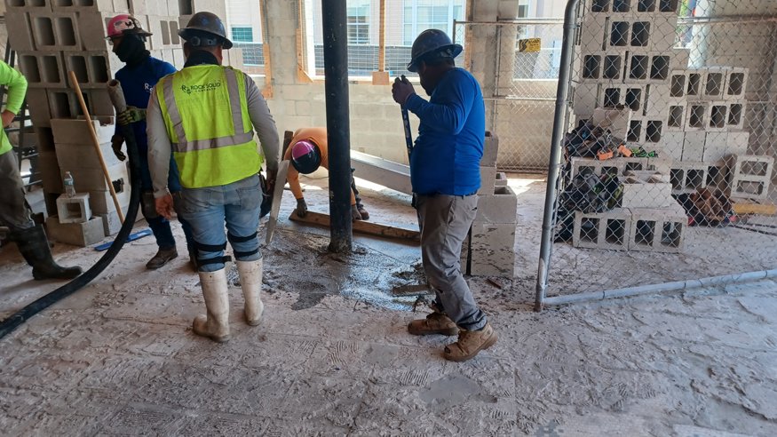 Construction workers reinforcing exposed foundation and slab areas at Peoples Bank, with rebar and mesh installed.