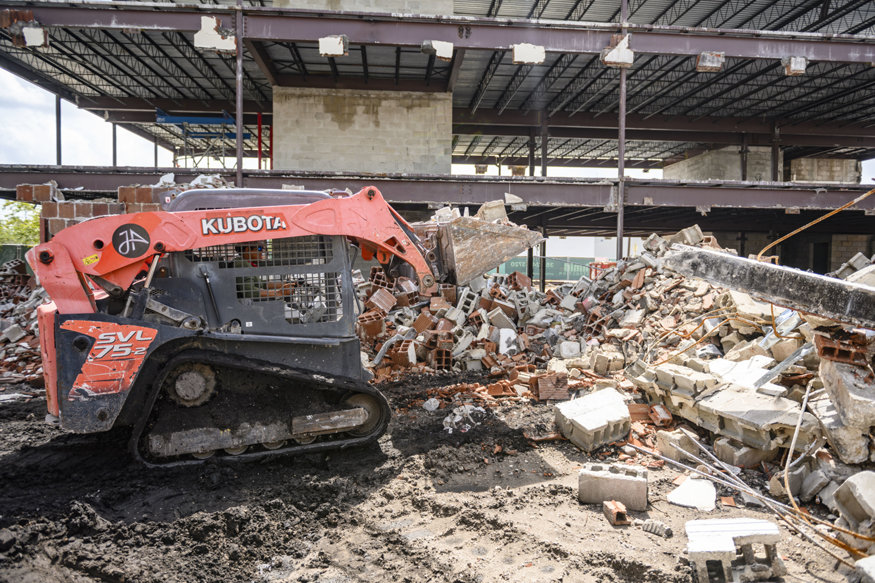 Loader clears masonry debris after exterior wall demolition.