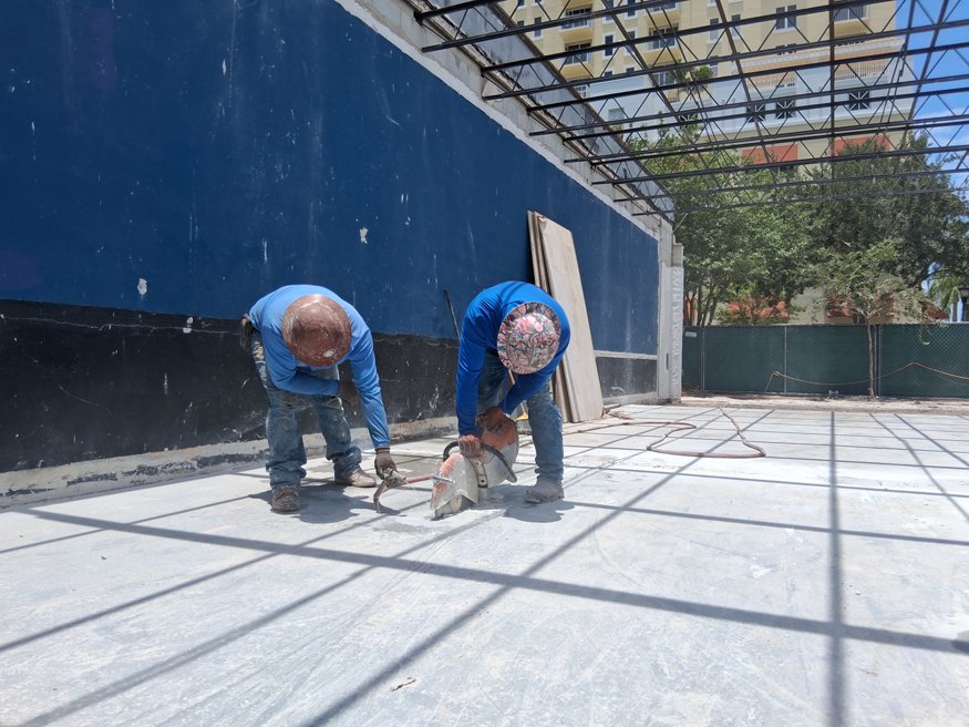 Workers saw cut concrete slab for utility trenching.
