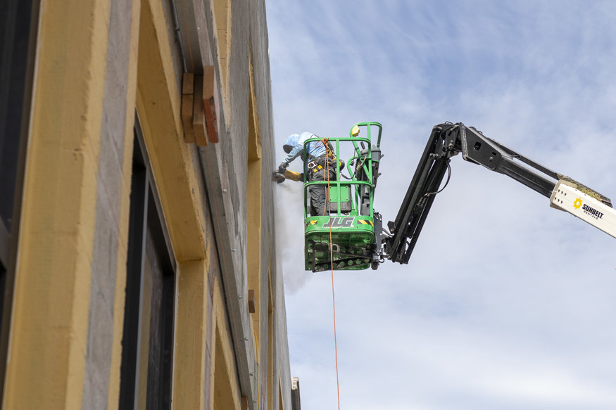 Worker using a lift for exterior preparation on the Peoples Bank building.