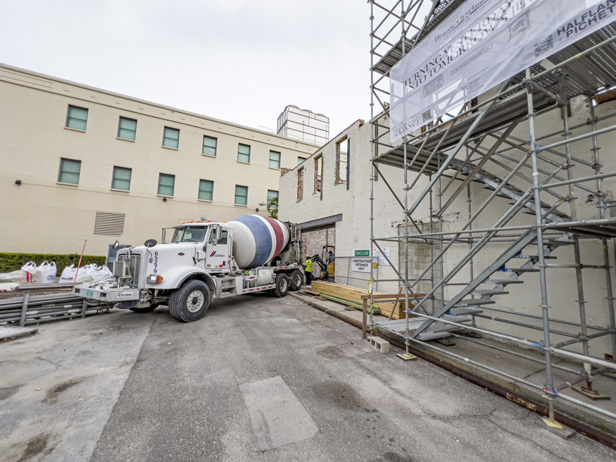 Cement mixer truck at the rear entrance of the Woolworth building, delivering concrete for elevator shaft work.