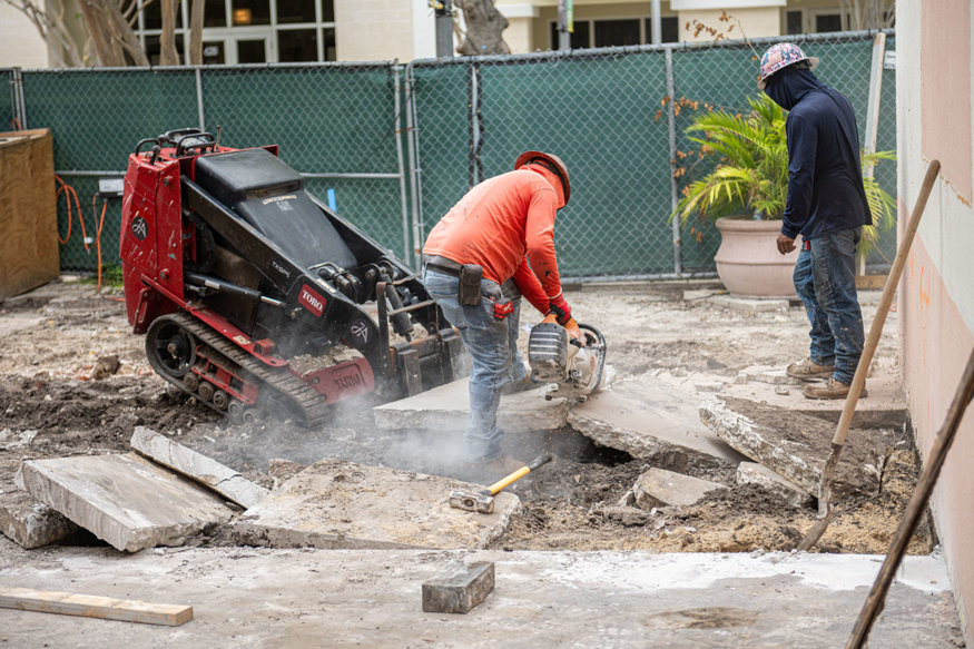 Crew member saw-cuts concrete slab into sections for removal.