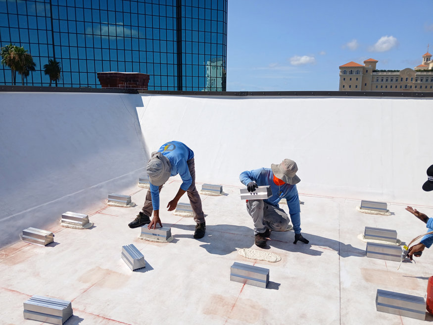 Technicians align solar brackets across roof for panel installation.