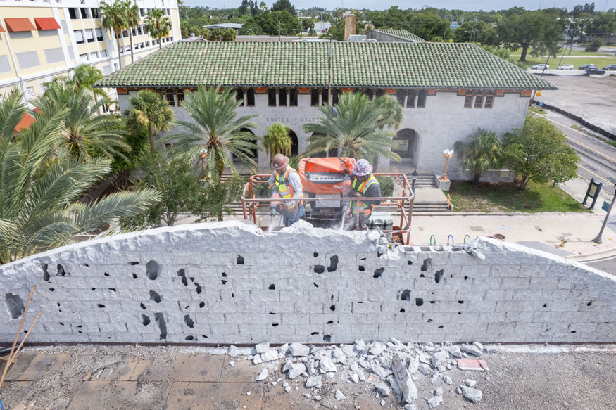 Crew removes parapet wall sections during rooftop demolition.