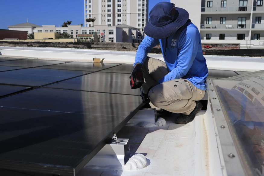 A solar panel is secured into place as the rooftop array expands.