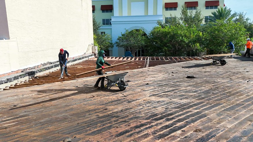 Workers remove wood planks from the roof deck.
