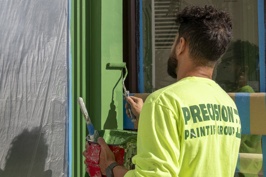 Roller brush painting green trim.