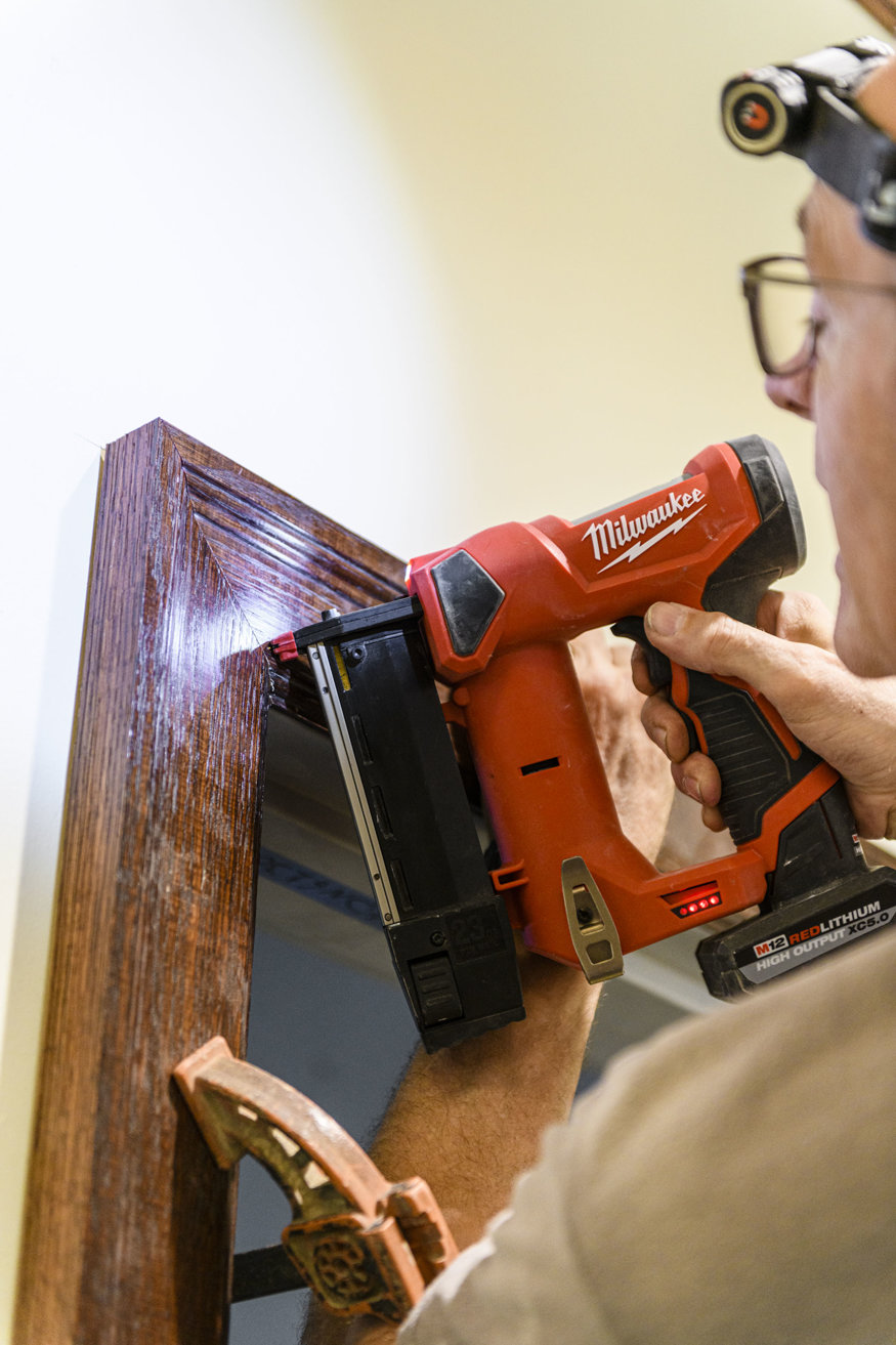 Worker installing wood door trim.