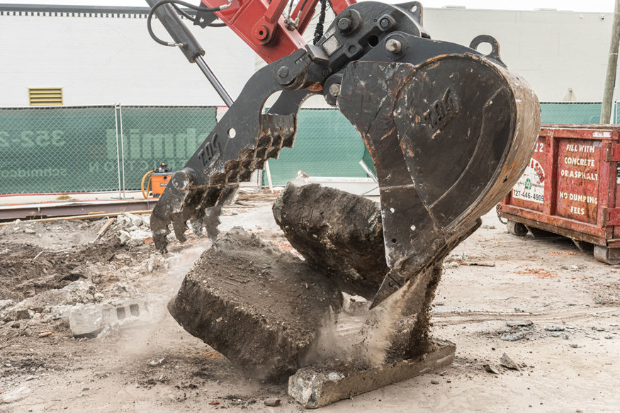 Excavator breaking concrete footing.