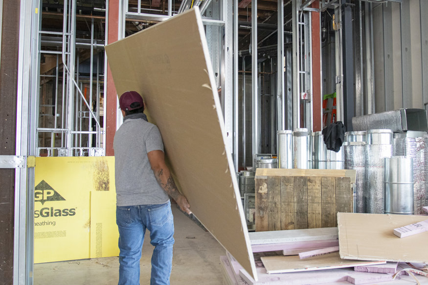 Carrying drywall panels during interior work.
