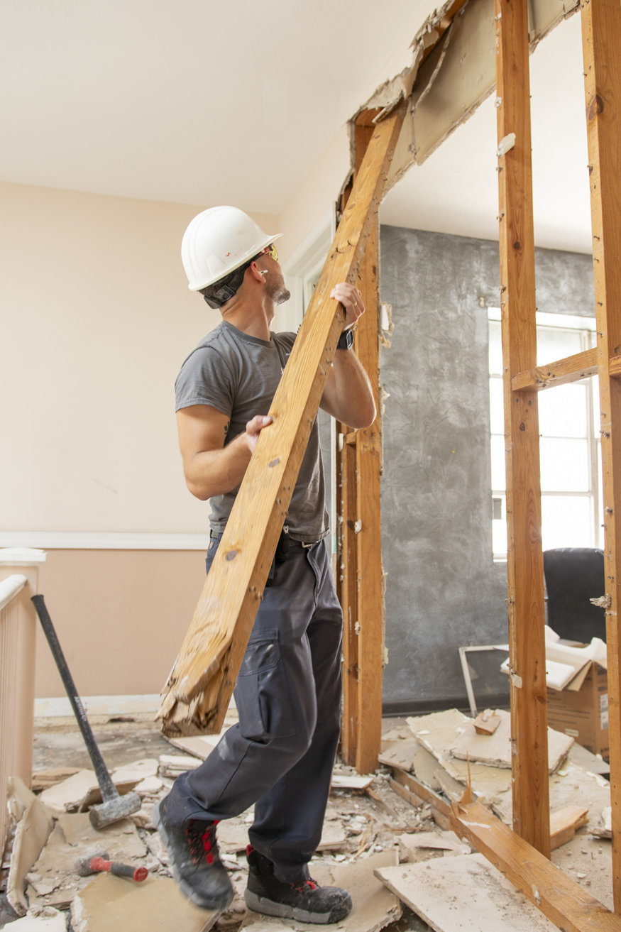 Worker using a hammer to remove a wall stud.