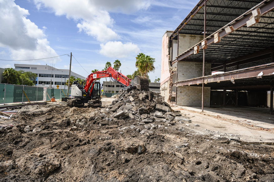 Excavator breaking concrete slab during demolition.