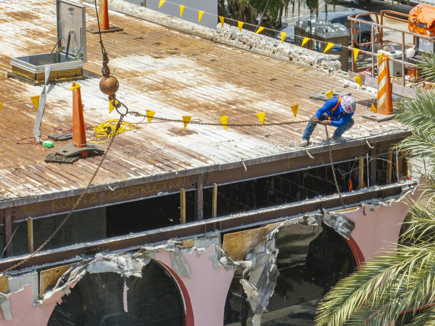 Worker guides chains during beam removal.