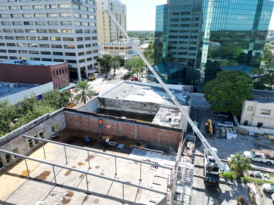 Overhead view of crane lowering steel beam into the Woolworth building.