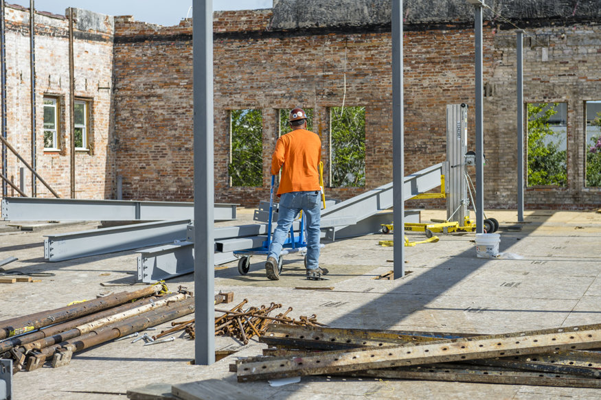 Worker moves steel beams across open floor of Woolworth building.