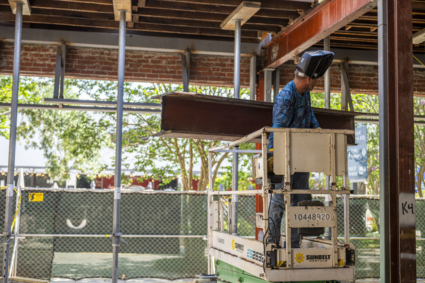 Worker in a lift maneuvers detached steel beam during Woolworth floor demolition.