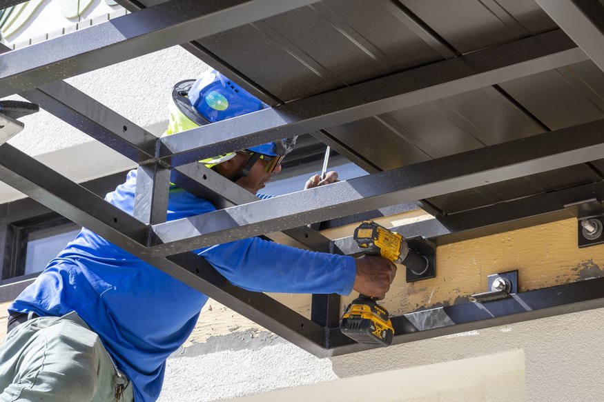 Drill tightening bolt on steel awning frame.