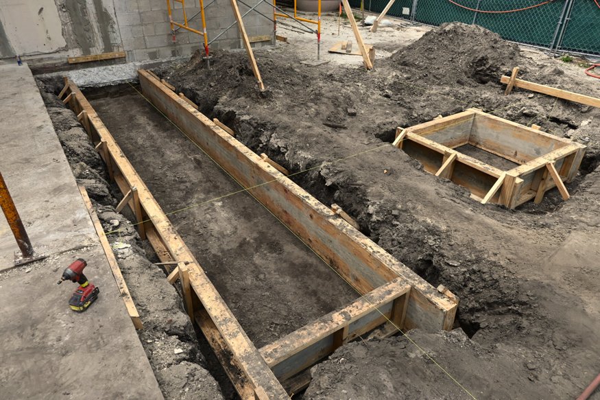 Installed wood forms define excavated foundation areas.