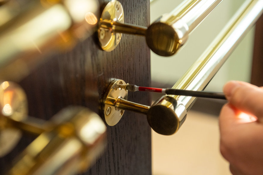 Close-up view of newly installed brass door hardware mounted on a dark wood lobby door.