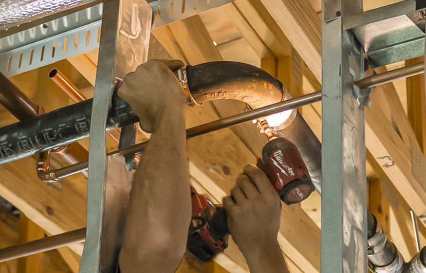 Worker aligning plastic drainpipes inside framing.