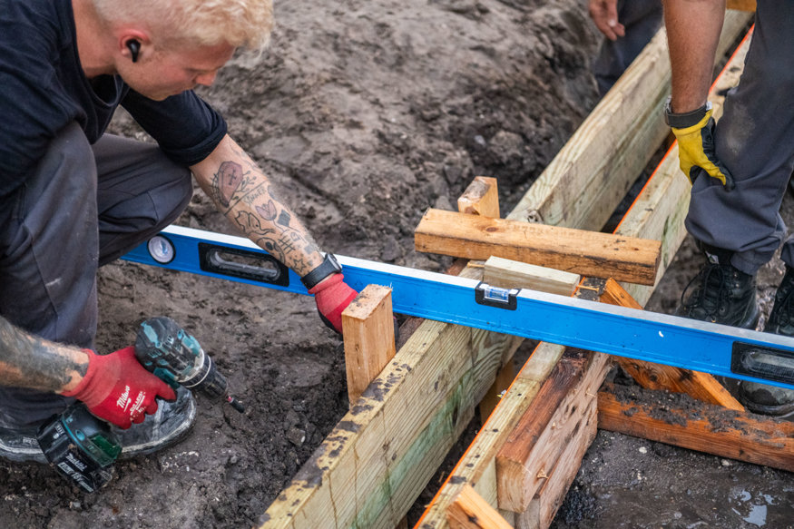 Crew secures wooden forms for concrete curb.