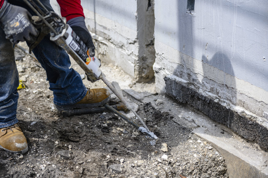 Worker anchors reinforcing bar at the base of the masonry wall.