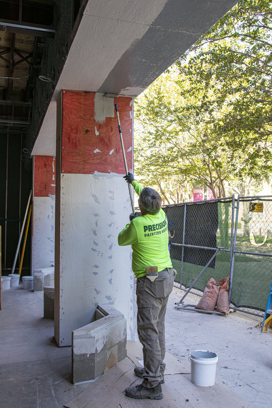 Worker applying waterproof coating with roller brush.
